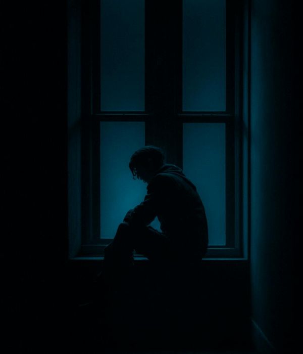Person meditating peacefully by a window with soft light.