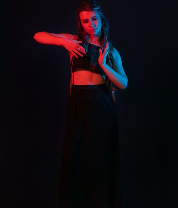 Woman performing a gentle yoga stretch in a dark room.